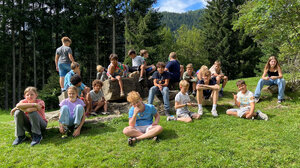 Bild zeigt ein Gruppenfoto mit Kindern der Freizeit 6 days, die auf einer Wiese sitzen und stehen.